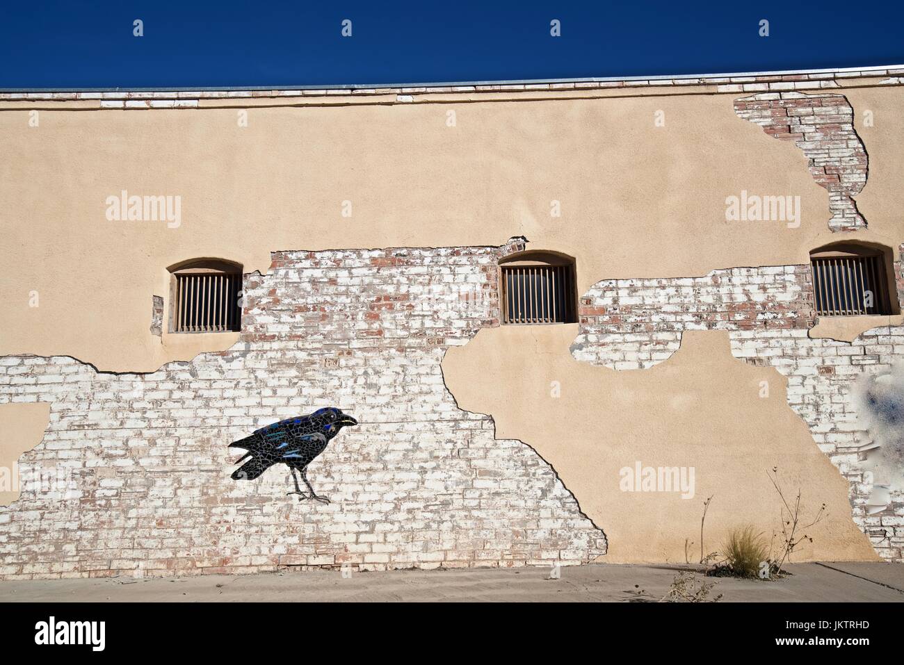 The front of an old adobe building with a raven painting on it in Mountain Air, New Mexico. Stock Photo