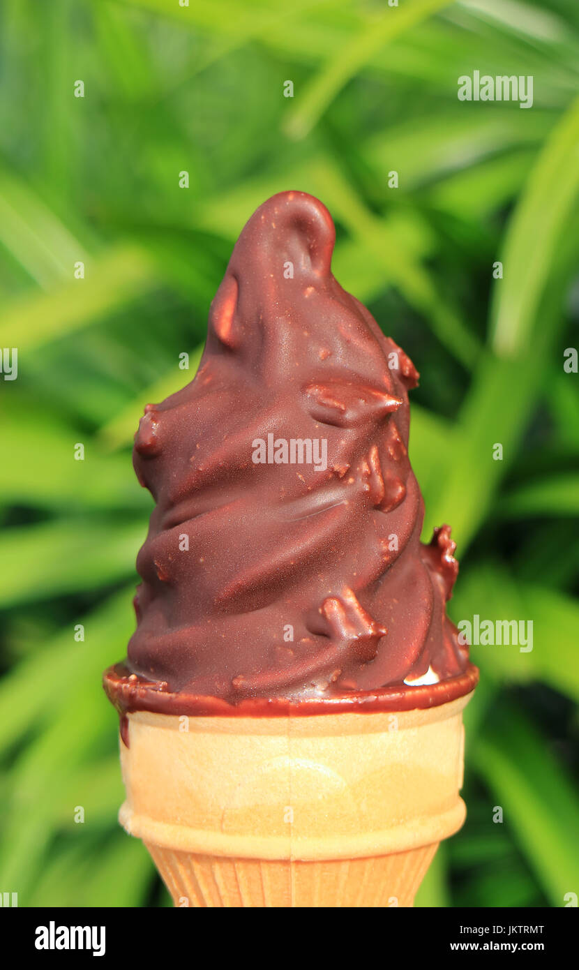 Closed up chocolate dipped soft serve ice cream cone, with blurred