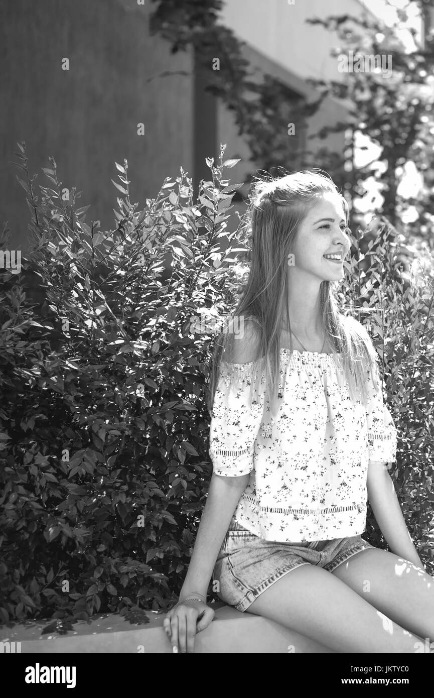 pretty cute young woman in yard house, near green bush, playfully laughing and smiling, in a good mood, sunny summer day Stock Photo