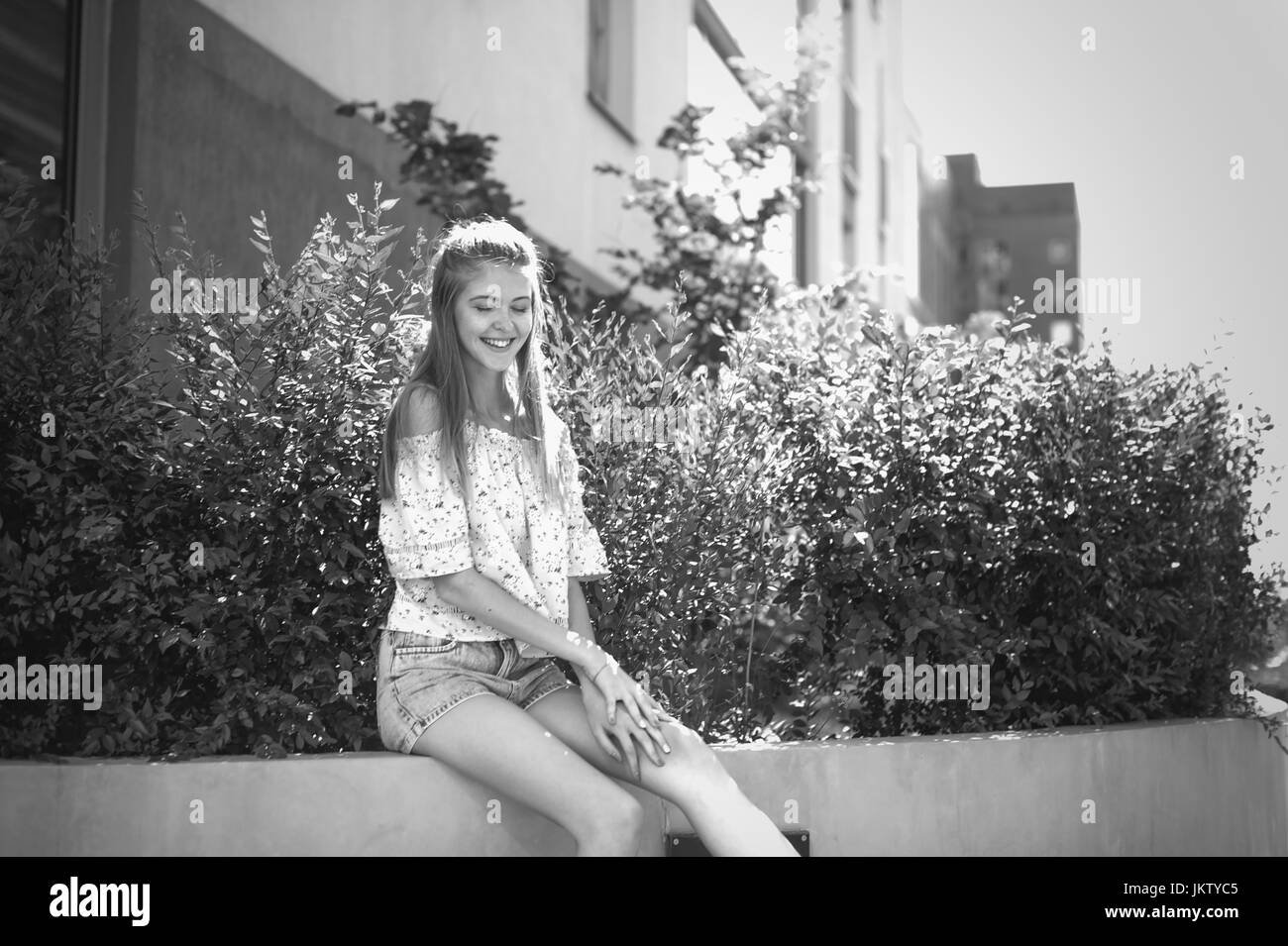 pretty cute young woman in yard house, near green bush, playfully laughing and smiling, in a good mood, sunny summer day Stock Photo