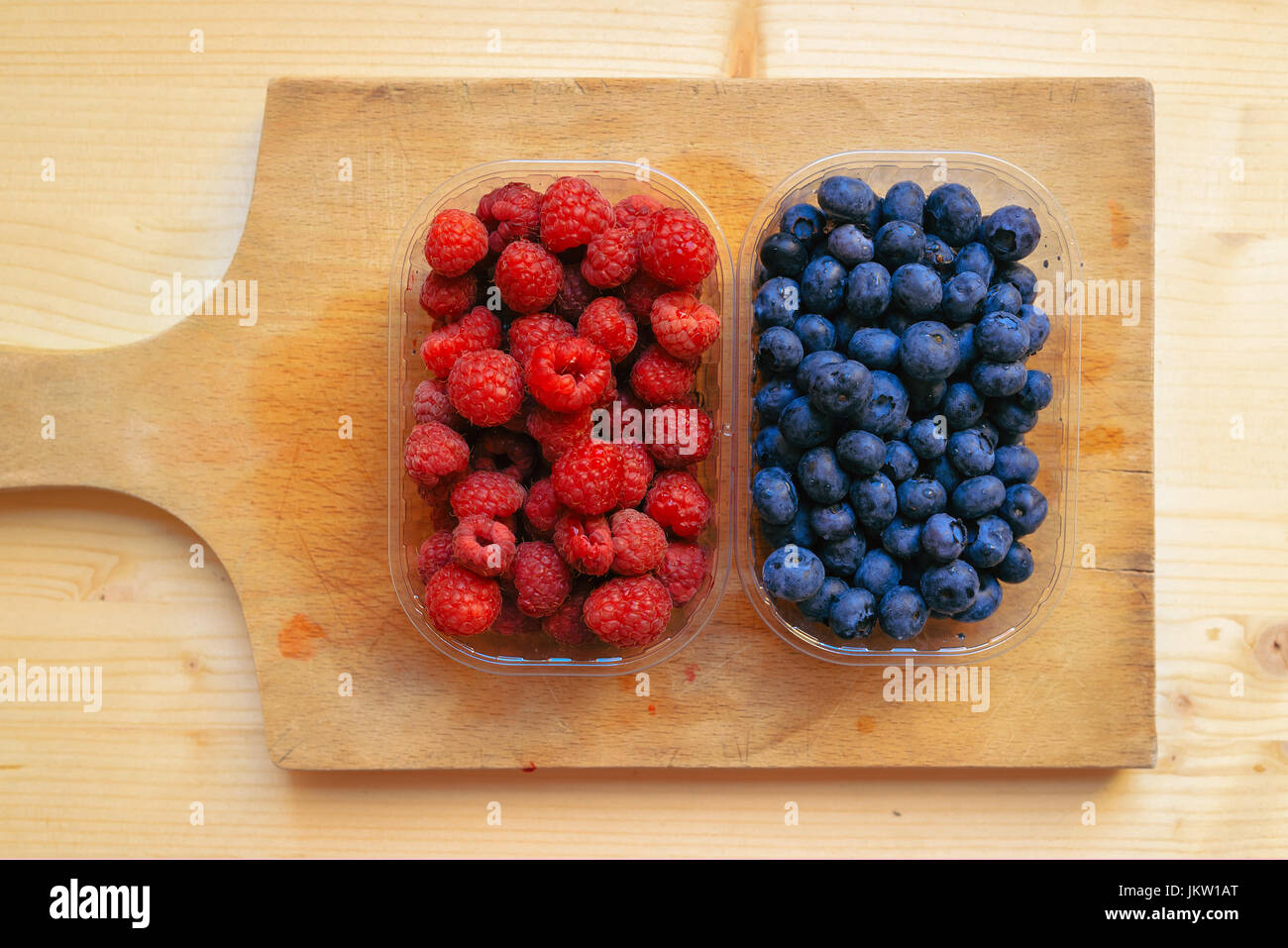 Blueberries and raspberries in plastic container boxes on wooden table ...