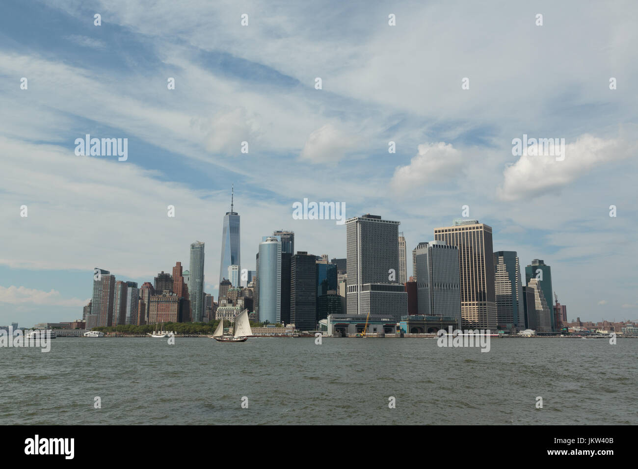 A photograph of Manhattan skyline, as seen from Governor's Island, New York City. An old sailing ship can be seen in the foreground. Stock Photo