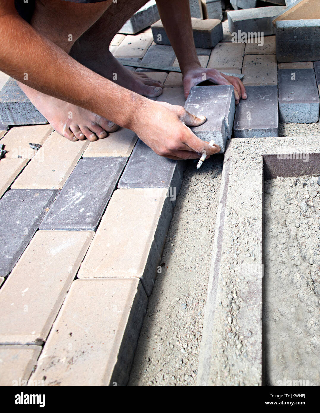 The worker puts the cut paving slab on the sidewalk along the curb