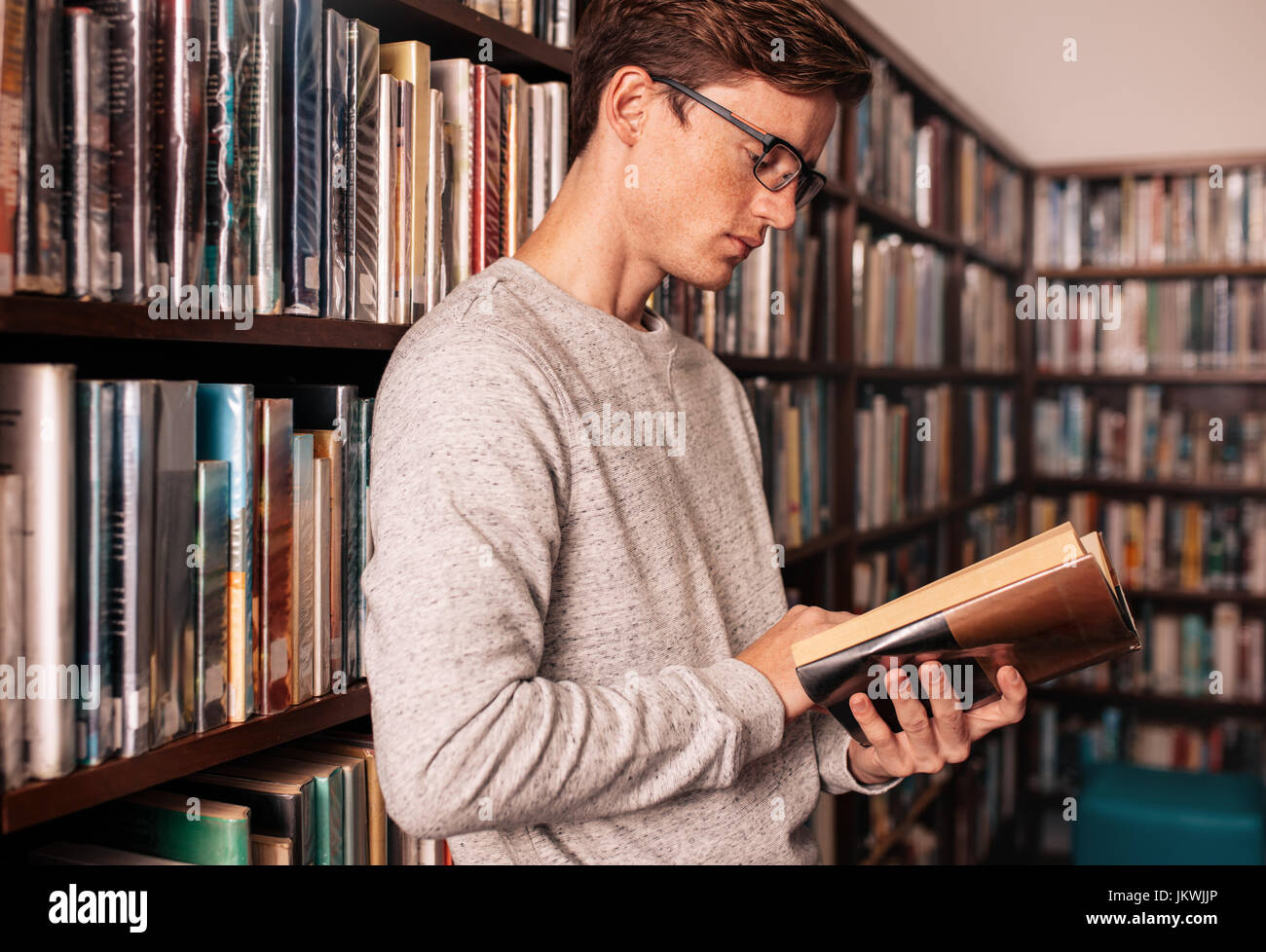Young university student reading a book in library. College student