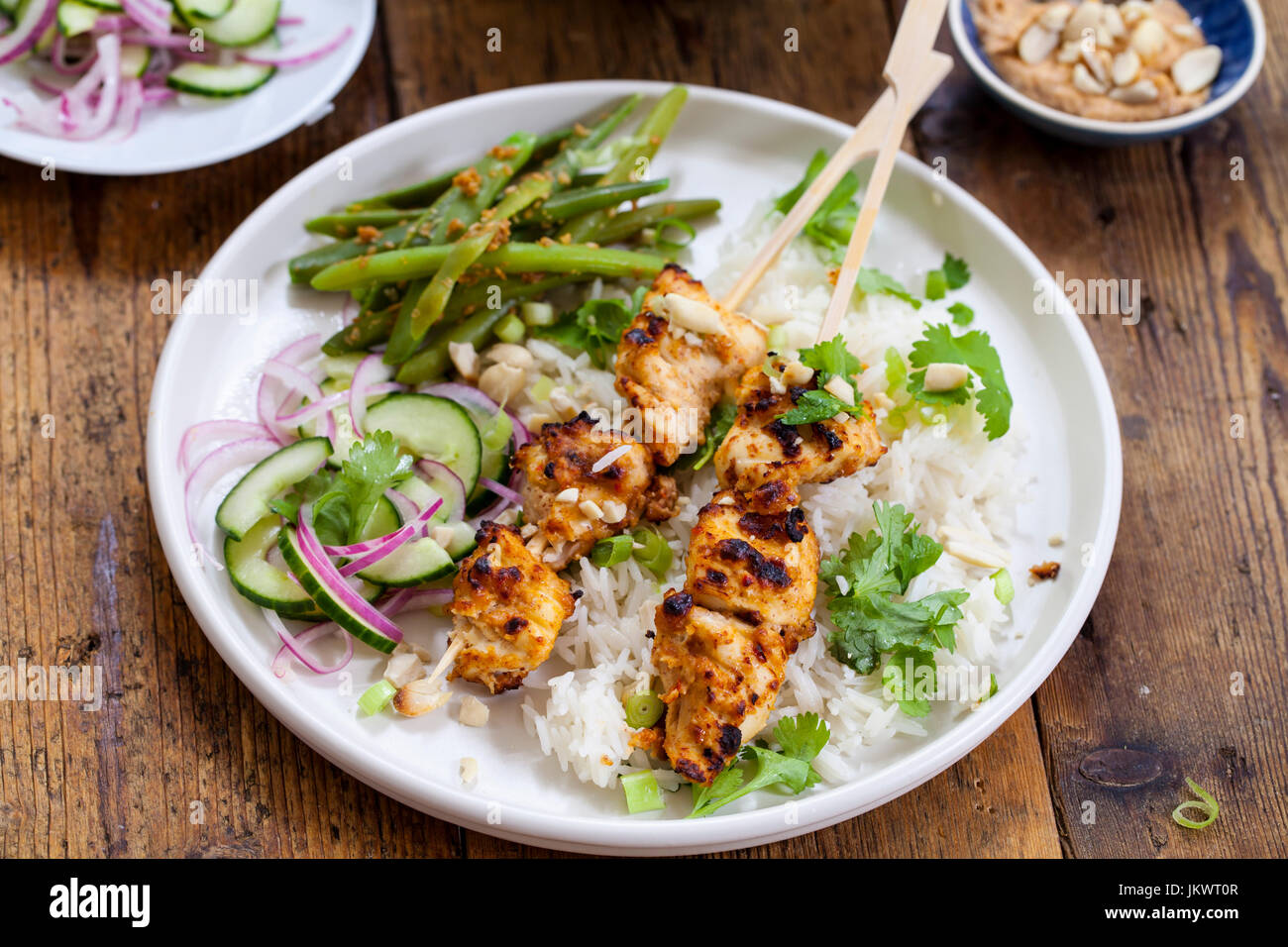 Satay chicken skewers with rice, cucumber salad and green beans Stock