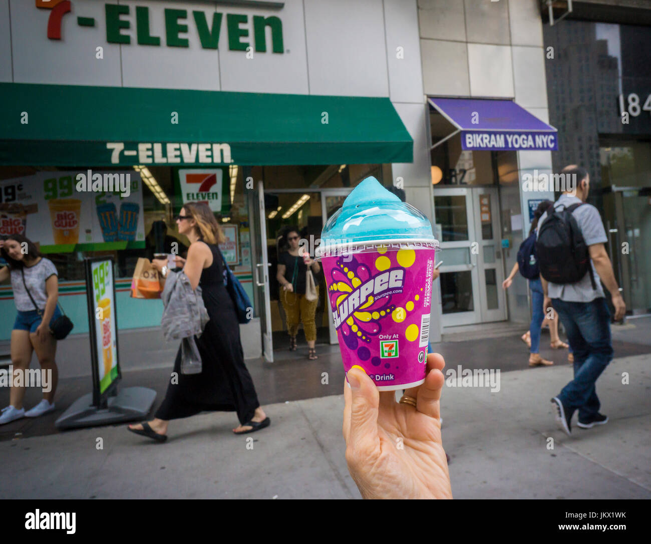 A Slurpee lover displays her free drink outside a 7-Eleven store in New York on Tuesday, July 11, 2017 (7-11, get it?), Free Slurpee Day! This year the chain is celebrating it's 90th birthday. The popular icy, slushy, syrupy drinks are available in regular and diet flavors, in combinations, and the stores have stocked up with extra barrels of syrup to meet the expected demand. According to the meticulous figures kept by 7-Eleven they sell an average of 14 million Slurpees a month and over 150 million Slurpees a year.  (© Richard B. Levine) Stock Photo