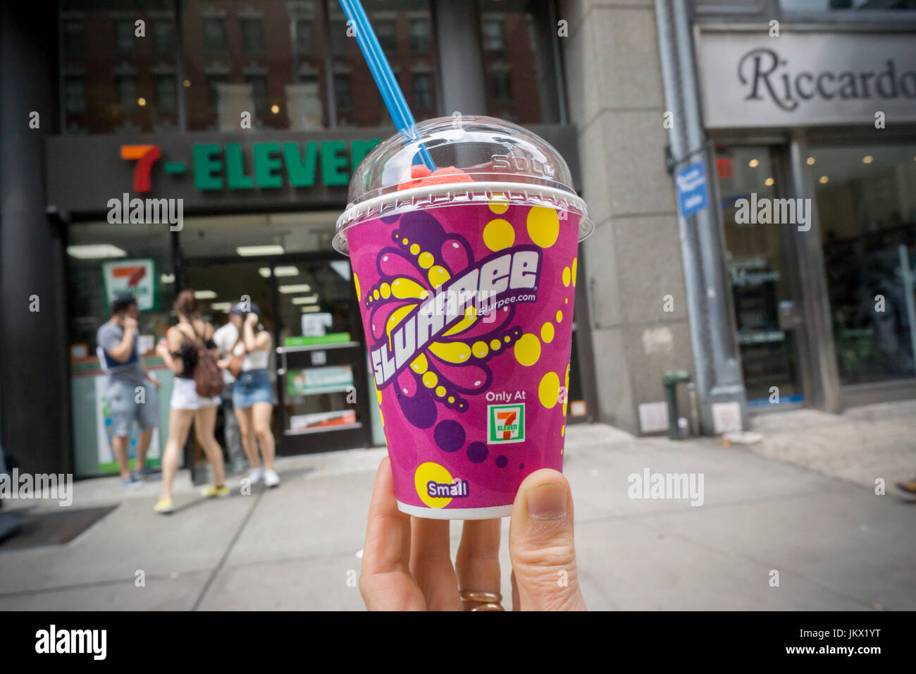 A Slurpee lover displays her free drink outside a 7-Eleven store in New York on Tuesday, July 11, 2017 (7-11, get it?), Free Slurpee Day! This year the chain is celebrating it's 90th birthday. The popular icy, slushy, syrupy drinks are available in regular and diet flavors, in combinations, and the stores have stocked up with extra barrels of syrup to meet the expected demand. According to the meticulous figures kept by 7-Eleven they sell an average of 14 million Slurpees a month and over 150 million Slurpees a year.  (© Richard B. Levine) Stock Photo