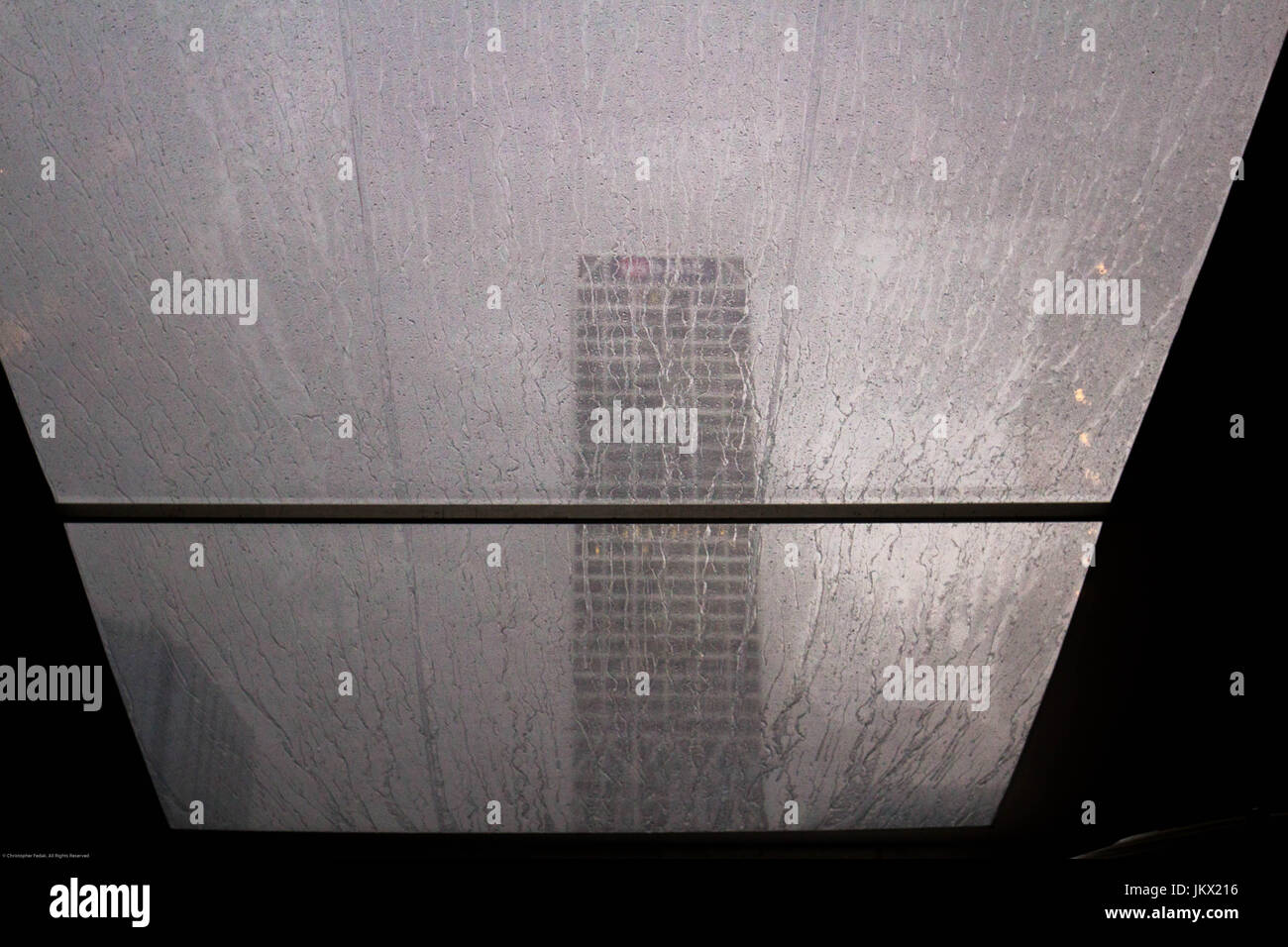 raindrops on a window with a single building in the distance Stock Photo