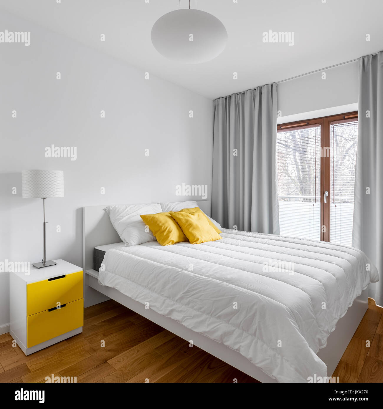 Big double bed in white and yellow home bedroom Stock Photo Alamy