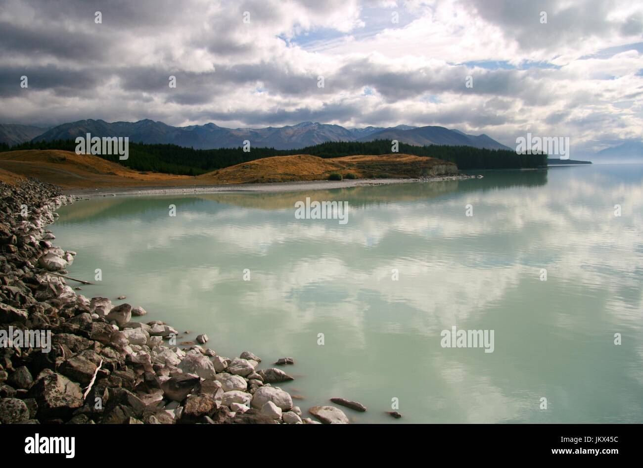 Moody Lake Pukaki with clouds reflecting in the water Stock Photo