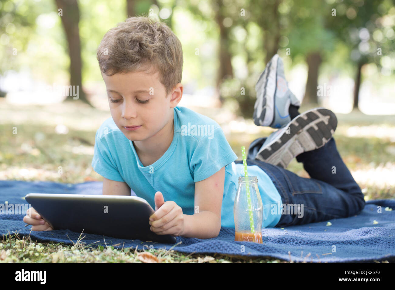 little cute boy of pre-school age uses a digital tablet while lying on ...