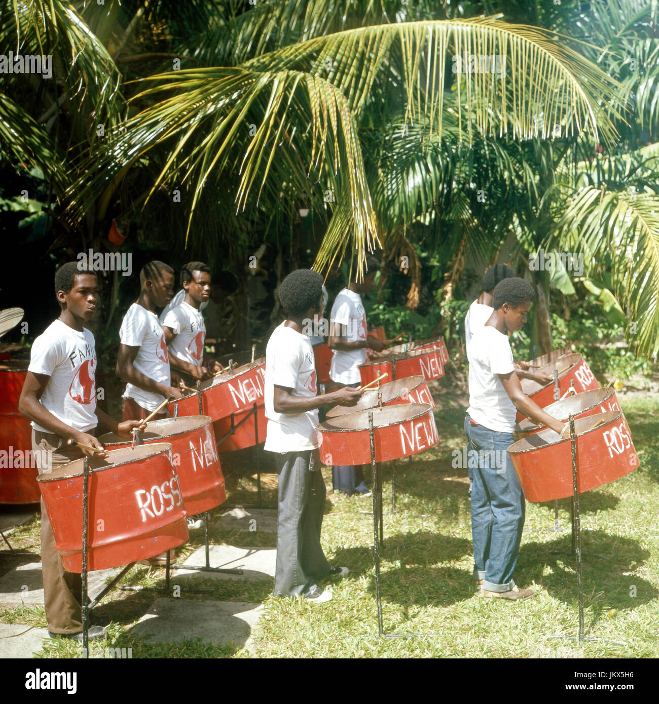 Musiker einer Steelband spielen in einem Garten auf Barbados auf, 1980er Jahre. Musicians of a steel band playing their tunes at Barbados, 1980s. Stock Photo