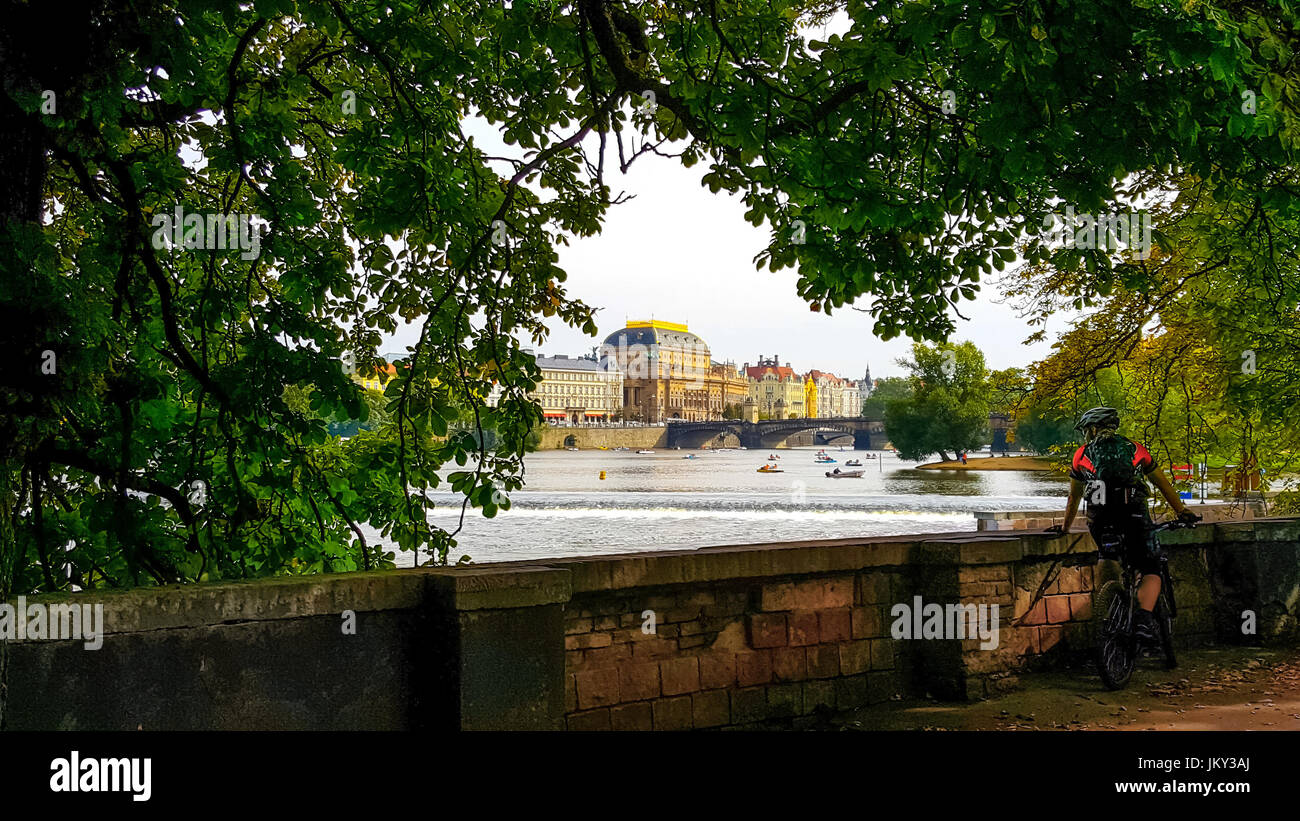 Bicyclist taking a break from his workout and enjoying the scenic view of the Vltava River in Prague Stock Photo