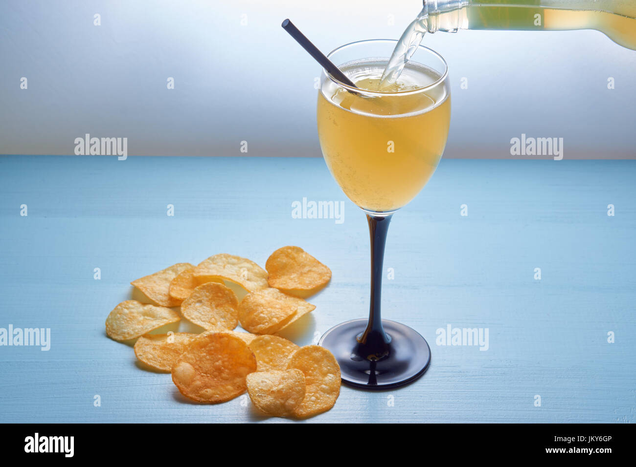 pouring cocktail mixed drink shake into glass with drinking straw and potato crisps. on clean blue background Stock Photo