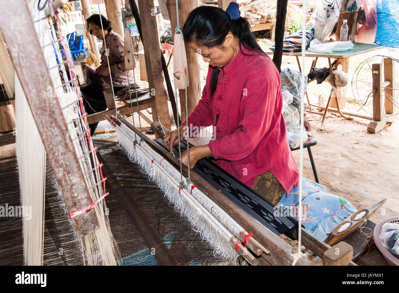 Thai ladies weaving cloth under a house in Nan,Isaan, Northern Thailand Stock Photo