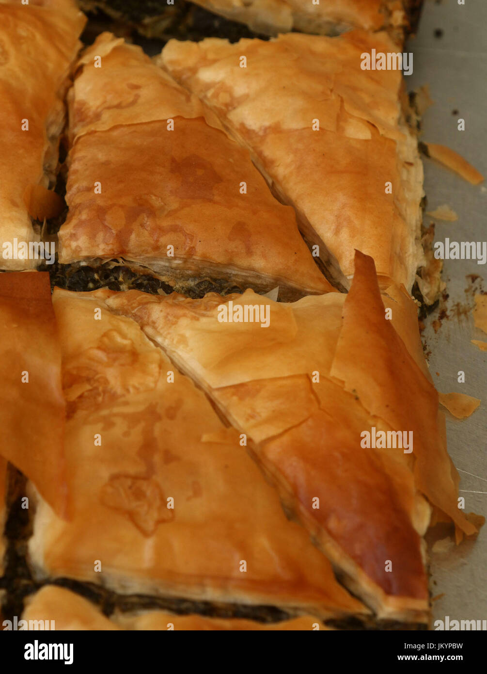 Spanakopita, also known as Spinach pie, a baked savory Greek dish made with phyllo pastry, layered with spinach and feta cheese on a baking tray Stock Photo