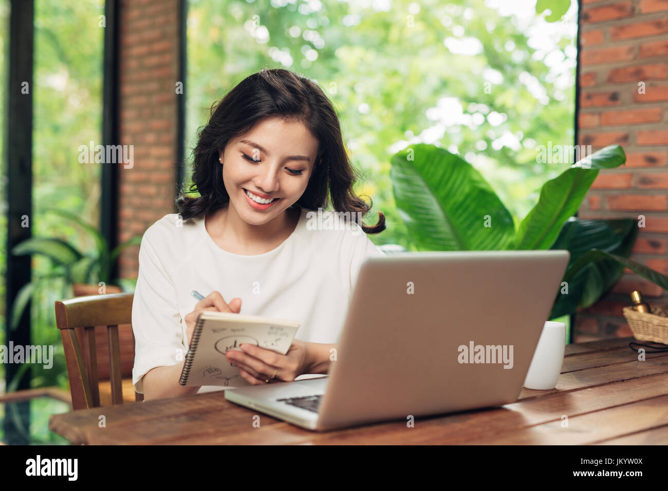 Beautiful young smiling woman working on laptop while sitting on bed at ...