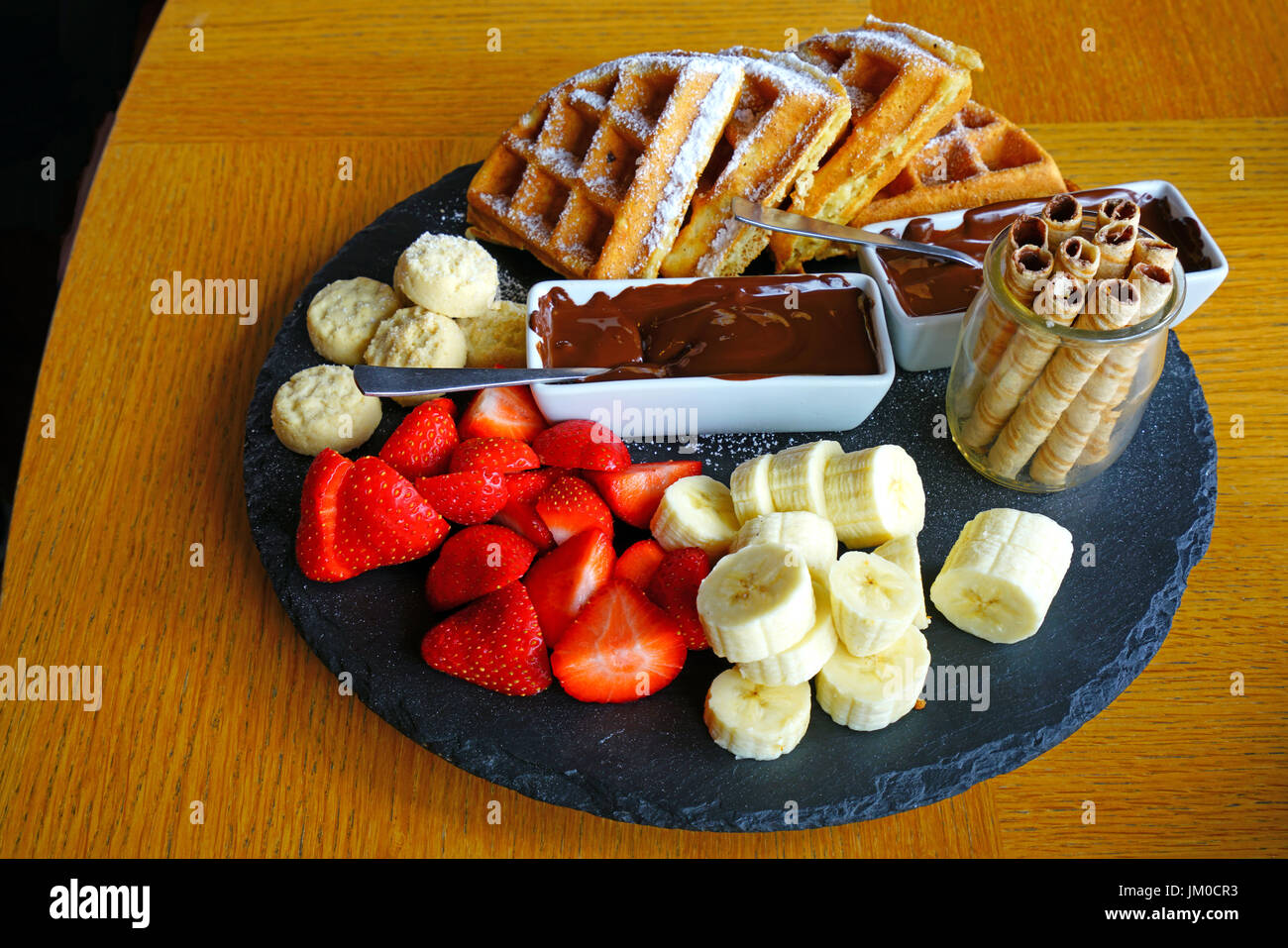 A vegan chocolate fondue platter with fresh fruit and waffles Stock