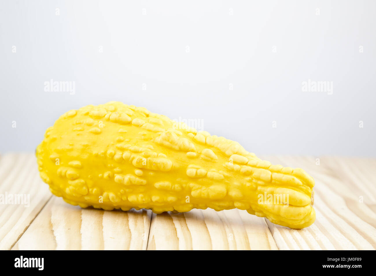 A decorative pumpkin (Yellow Crookneck) lying on wood with background for a text Stock Photo