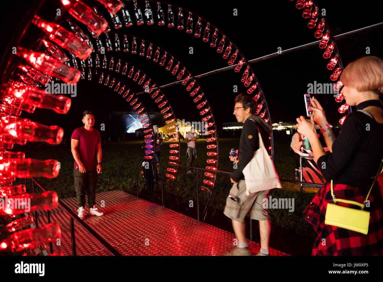 BONTIDA, ROMANIA - JULY 13, 2017: Empty Coca Cola bottles are arranged in a shape of a tunnel and illuminated with red lights at Electric Castle festi Stock Photo