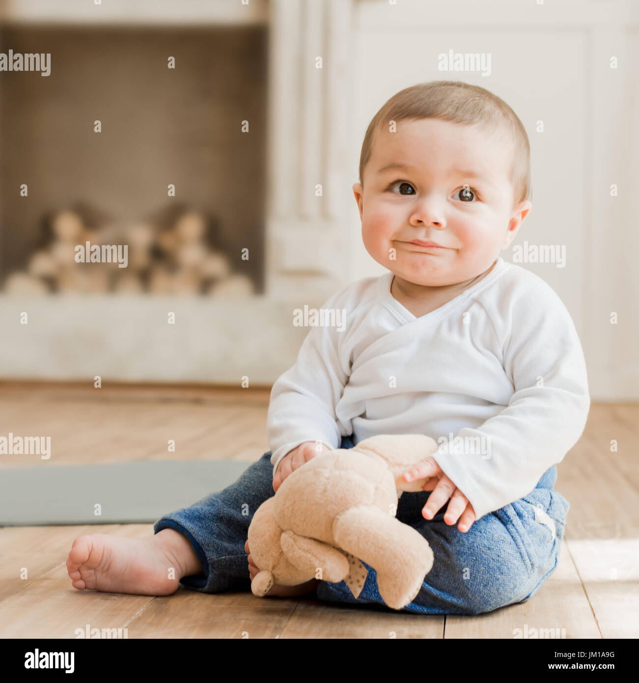 Smiling baby boy sitting with teddy bear toy on the floor Stock Photo ...
