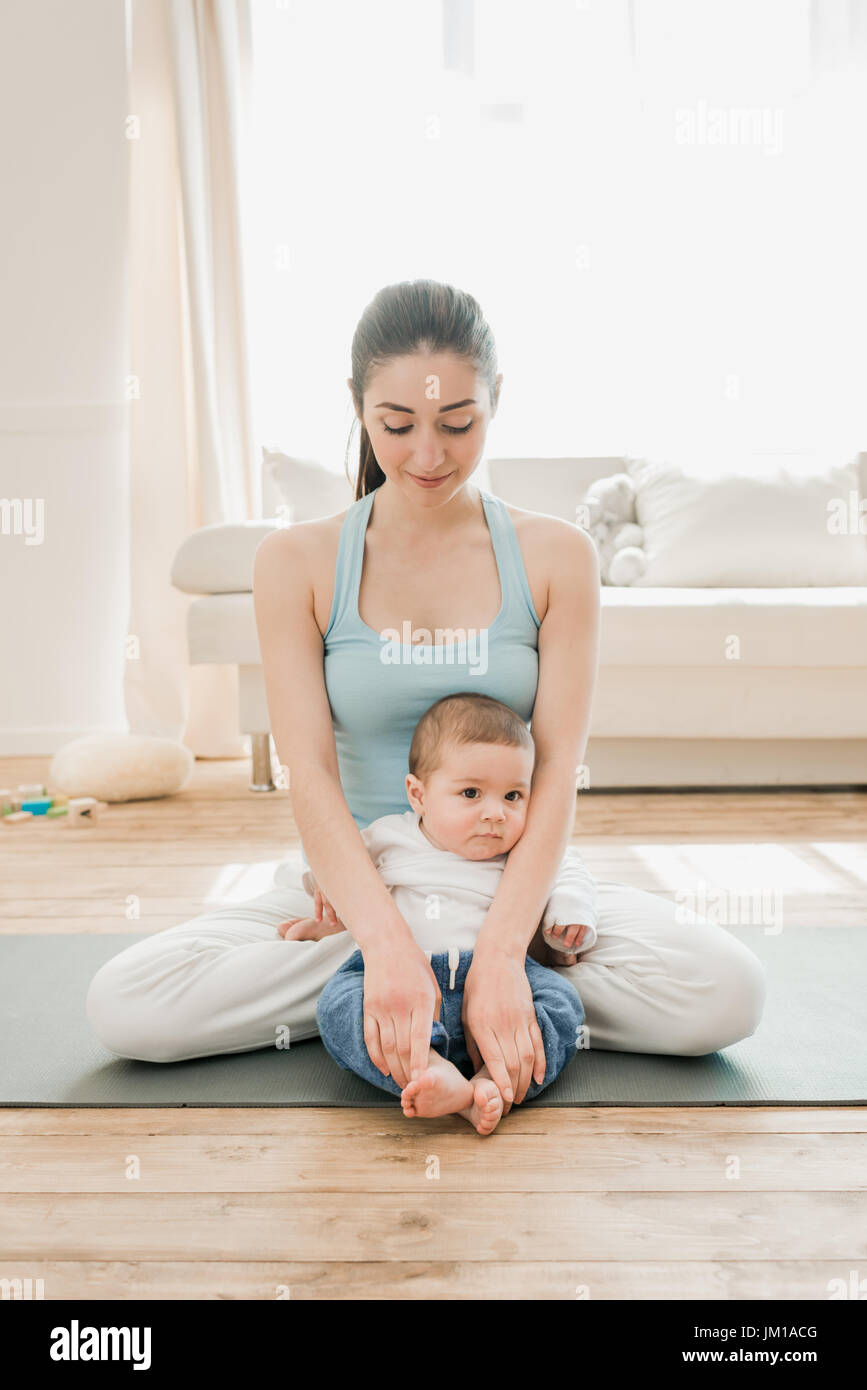 Smiling woman sitting in lotus position with her little child Stock Photo