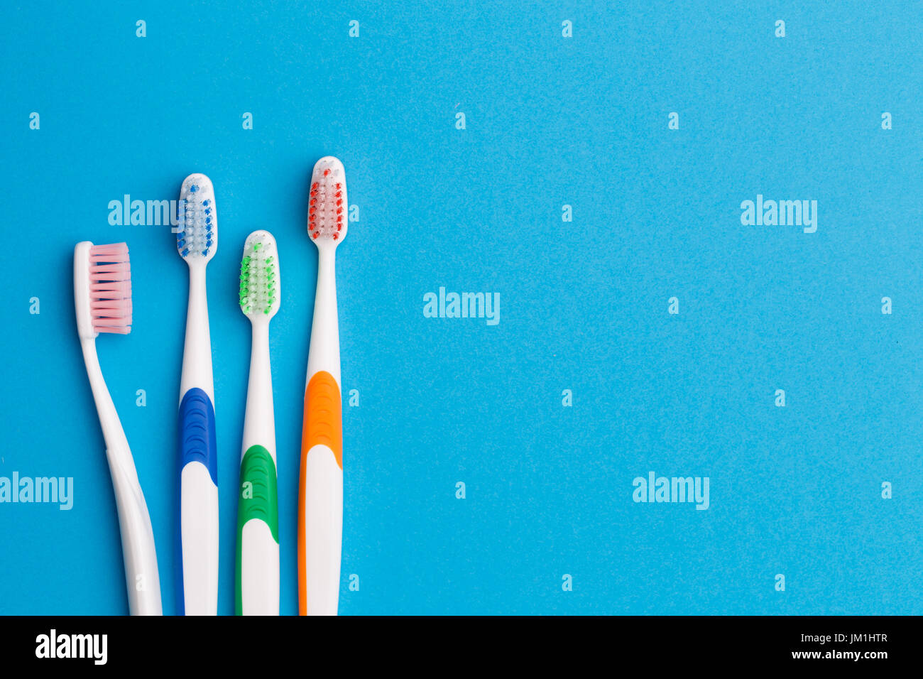 Multi-colored toothbrushes on blue background, space for text Stock Photo