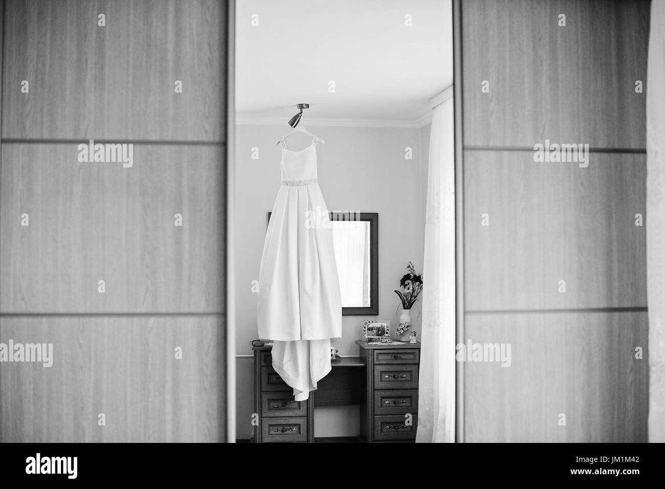 Wedding dress hanging on the rack in the room. Black and white photo ...