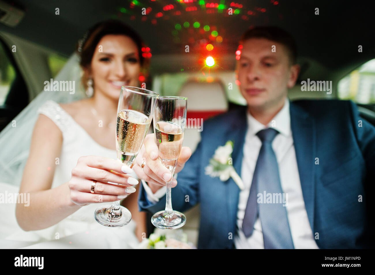 Newly married couple drinking champagne in the limousine on their