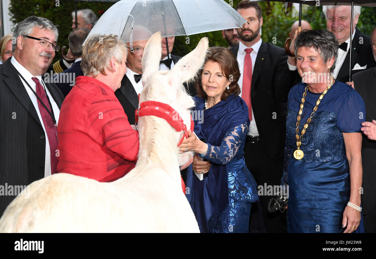 Bayreuth, Germany. 25th July, 2017. Mayoress of Bayreuth Brigitte Merk-Erbe (r-l), Sweden's Queen Silvia, Sweden's King Carl Gustaf (hidden) and two staff members from the Neusiedler See National Park with a white donkey, pictured at the opening of the Bayreuth Festival in Bayreuth, Germany, 25 July 2017. The donkey was brought into the garden of the Festspielhaus by the national park staff to show the Swedish royal couple. Photo: Tobias Hase/dpa/Alamy Live News Stock Photo