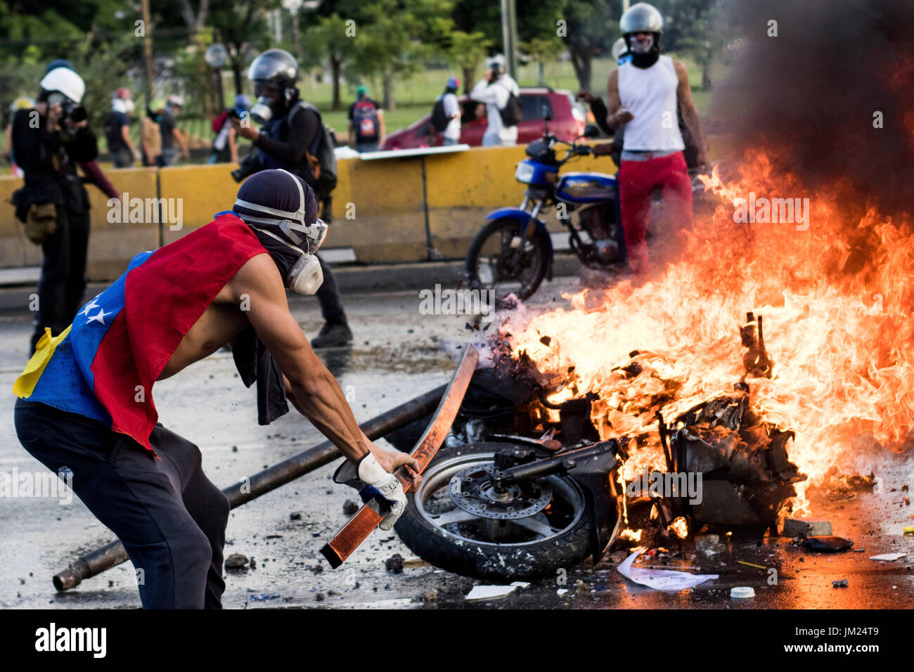 Caracas, Venezuela. 22nd June, 2017. An anti-government demonstrator stands by a burning motorcycle protesters took away from National Guards who blocked them from marching to the office of Attorney General Luisa Ortega Diaz to show support for the one-time government loyalist. Venezuela's Supreme Court cleared the way for the prosecution of the country's chief prosecutor, who became a surprise hero to the opposition after breaking ranks with the government of President Nicolas Maduro over his efforts to concentrate power. Credit: Elyxandro Cegarra/ZUMA Wire/Alamy Live News Stock Photo