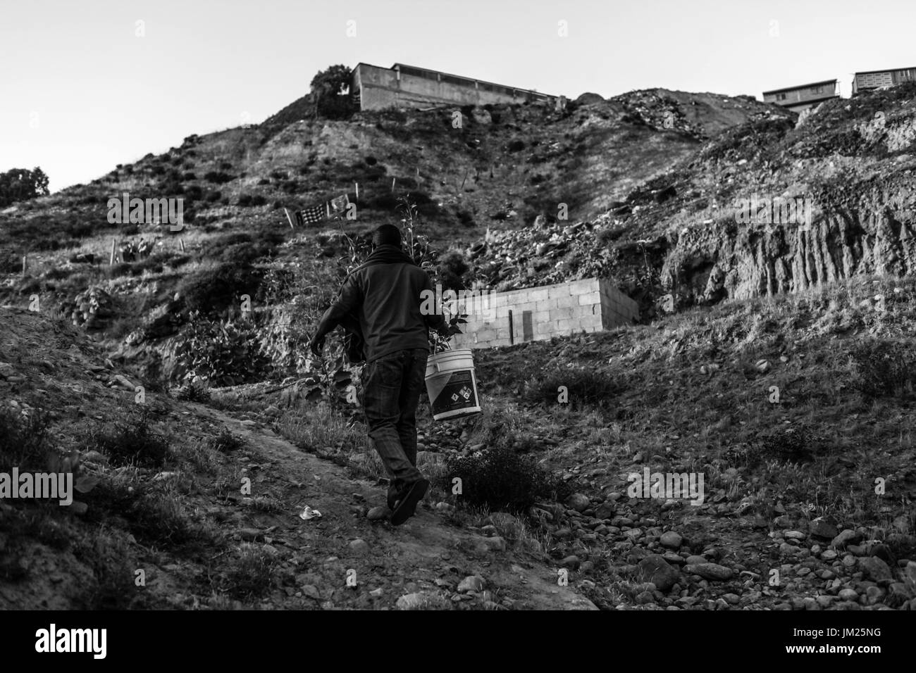 Tijuana, Baja California, Mexico. 27th June, 2017. A Haitian migrant walks up a hill to gather water outside the Iglesia Evangelica Embajadores de Jesus in Tijuana, Baja California. Haitian migrants found themselves stuck in Mexico after their hopes of crossing into the United States were halted as a result of immigration policies. Credit: Joel Angel Juarez/ZUMA Wire/Alamy Live News Stock Photo