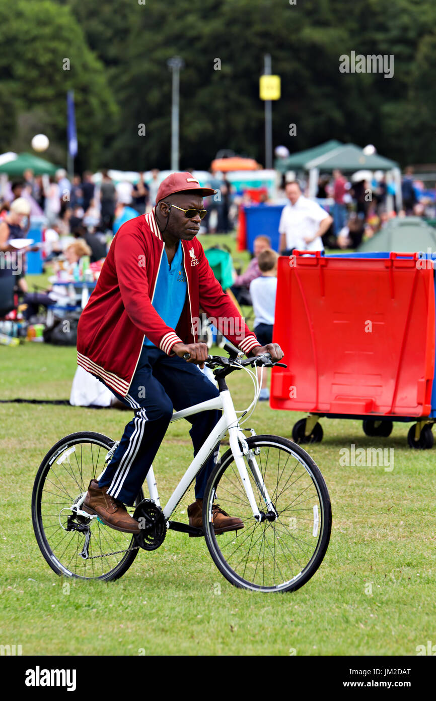 Cool black man in shades arriving at an outdoor music festival on his bike Stock Photo