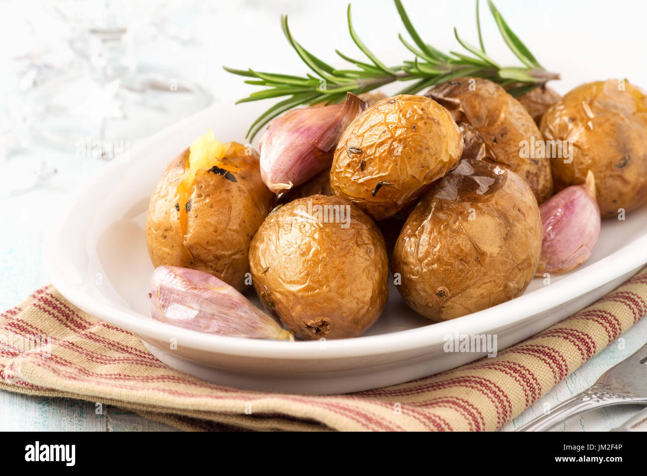 Oven baked potatoes or jacket potatoes with rosemary and garlic cloves