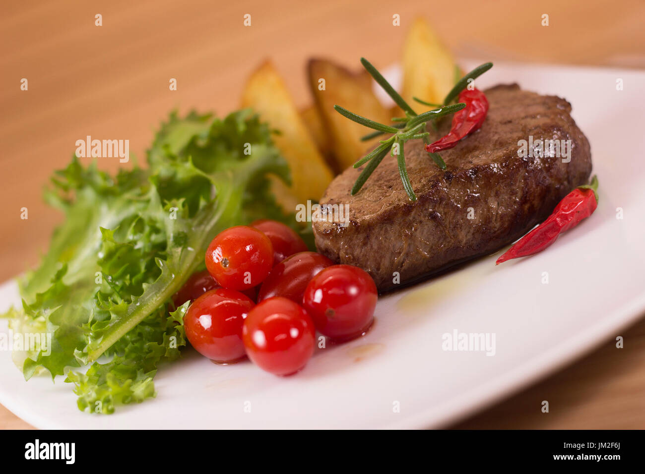 Fillet mignon steak with green salad and home made potatoes. Selective focus on meat. Stock Photo