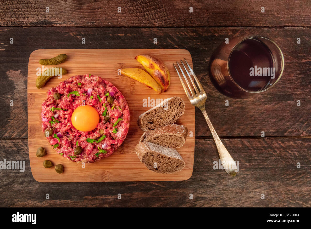 Steak tartare with garnish, red wine, and copyspace Stock Photo - Alamy