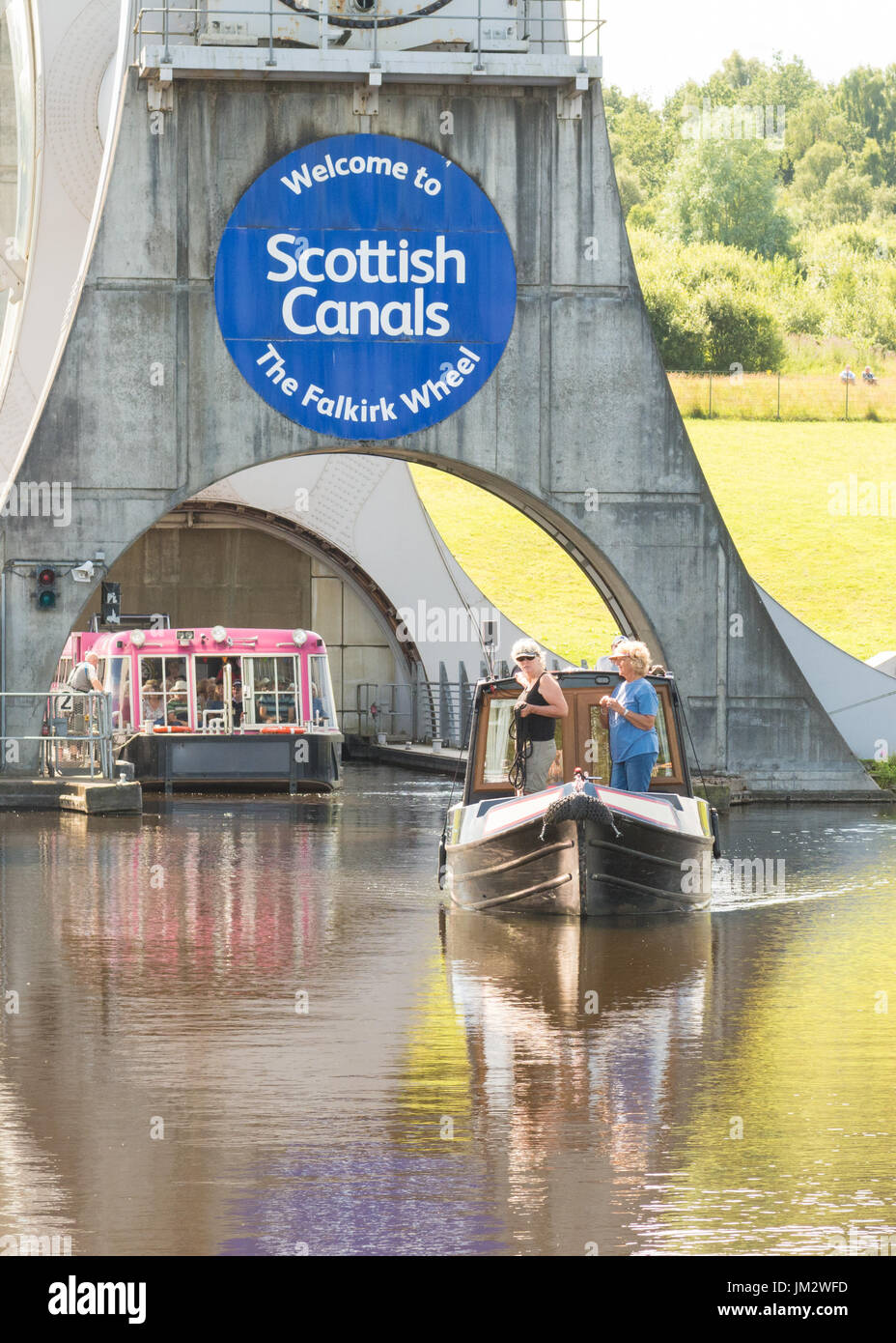 Falkirk Wheel, Scotland - private pleasure narowboat and the pink visitor boat leaving the bottom of the wheel Stock Photo