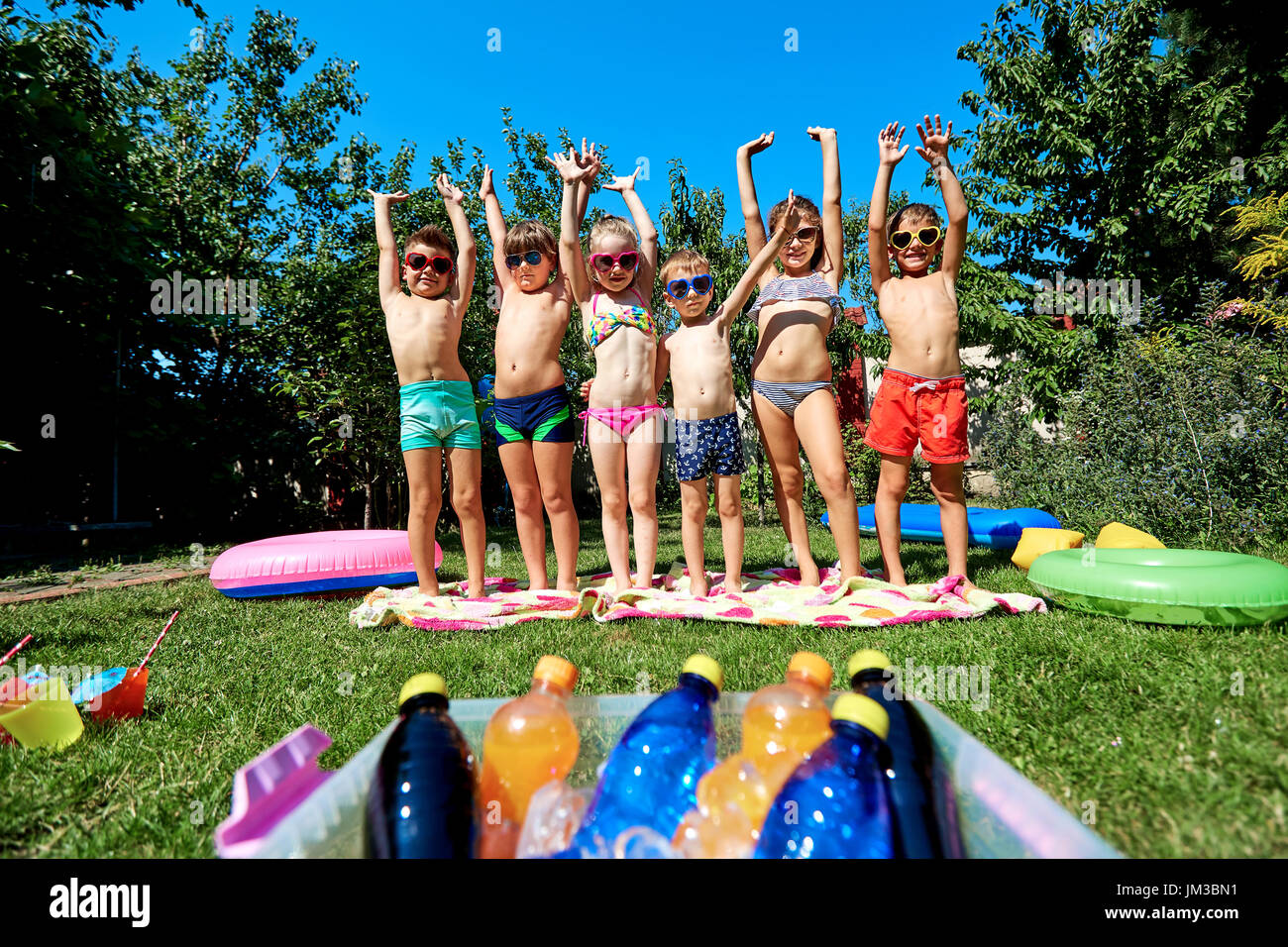 Group of children in swimsuit with arms raised  in summer. Stock Photo