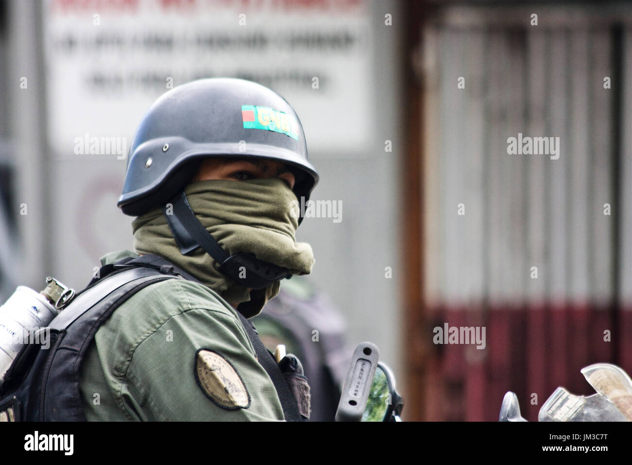 A member of the Bolivarian National Guard covering his face with a t-shirt because they don´t have enough gas masks, during a protest against Maduro. Stock Photo