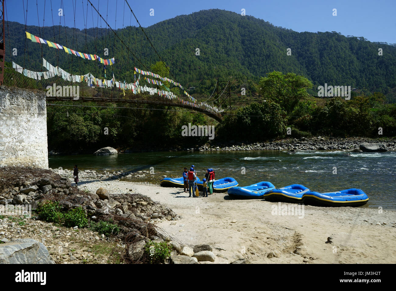 Boaters prepare rafts below suspension bridge ion Punakha river, Bhutan Stock Photo
