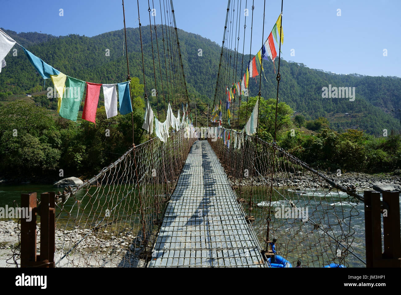 Suspension bridge across upper Punakha river with rafter getting ready to float, Bhutan Stock Photo
