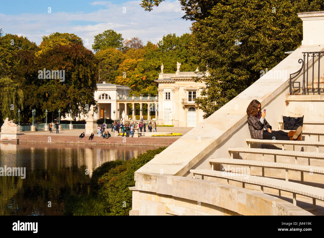 Warsaw, Poland - October 2, 2014: Young girl relaxing on a bench of The Amphitheatre in Lazienki Krolewskie park (Royal Baths park), the Water Palace  Stock Photo