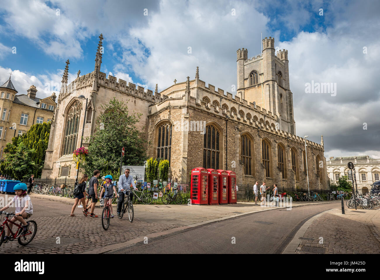 A family on bicycles cycle through Cambridge near the Church of St. Mary's the Great on St. Mary's Street, Cambridge, UK Stock Photo