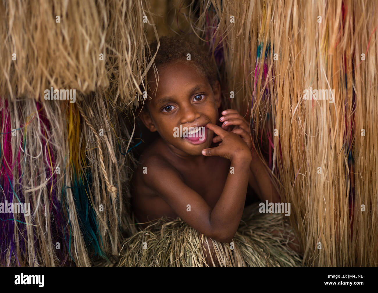 Girl hiding in the grass skirt of her mother, Tanna island, Yakel, Vanuatu Stock Photo