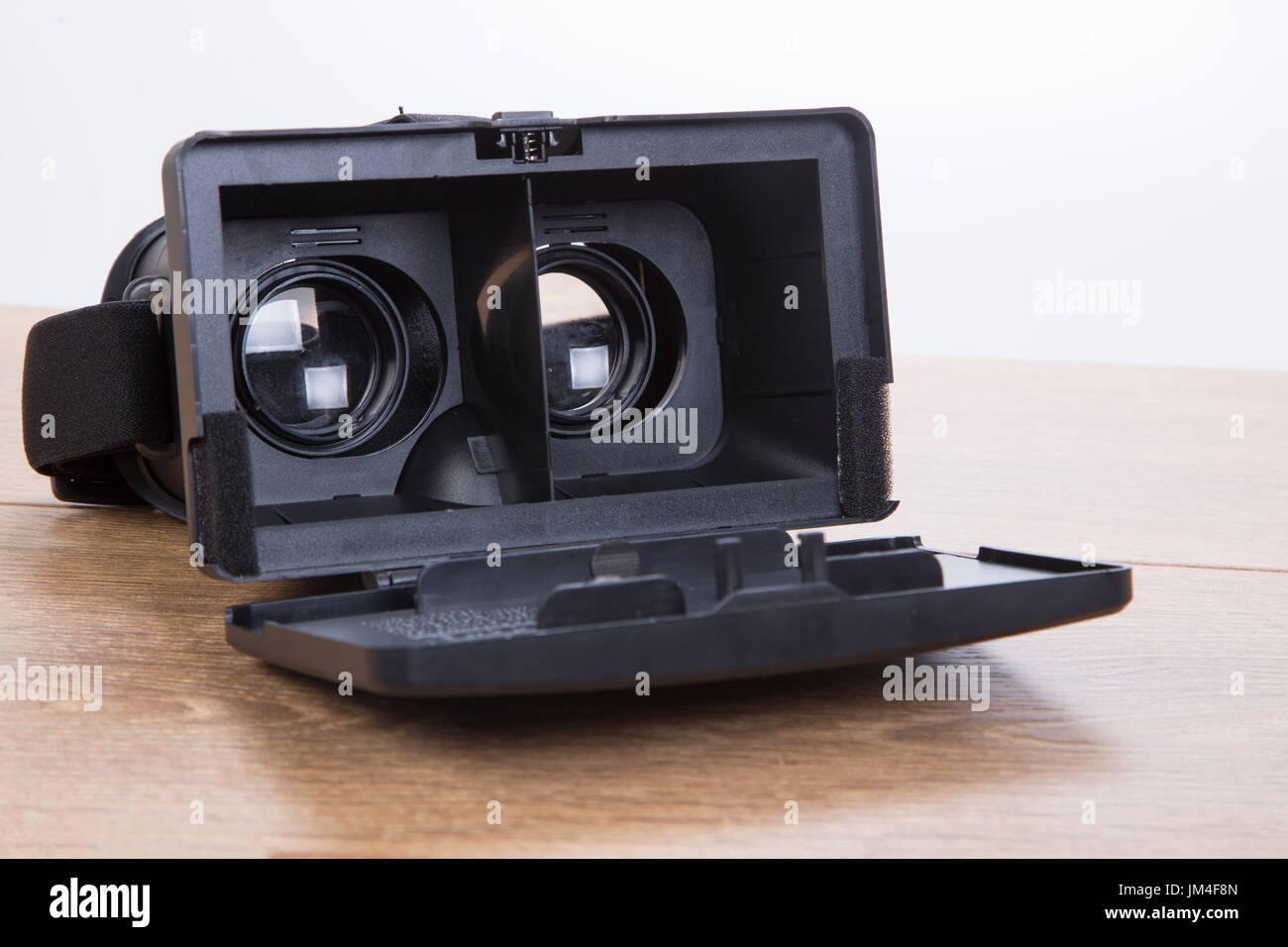 Open 3d VR virtual reality goggles or headset showing the optical lenses for creating simulated three-dimensional environments on a wooden desk in a c Stock Photo