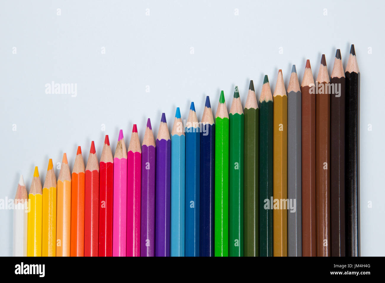 Coloured pencils laid flat on pale blue paper Stock Photo