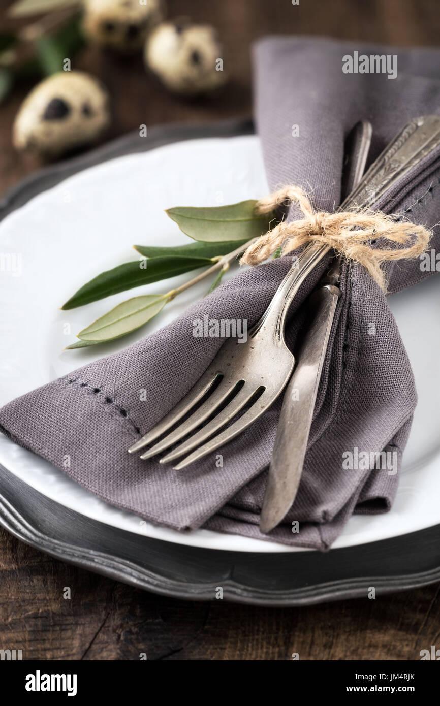 Easter table setting with vintage silverware with an olive branch on a white plate with quail eggs at the background Stock Photo