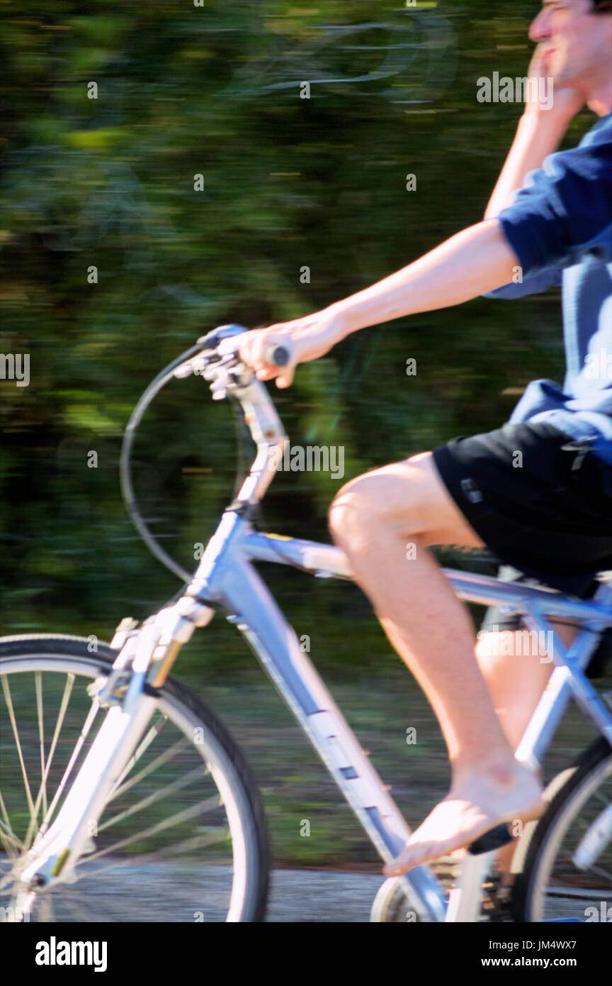 A blurred man talking on a phone on a bicycle. Stock Photo