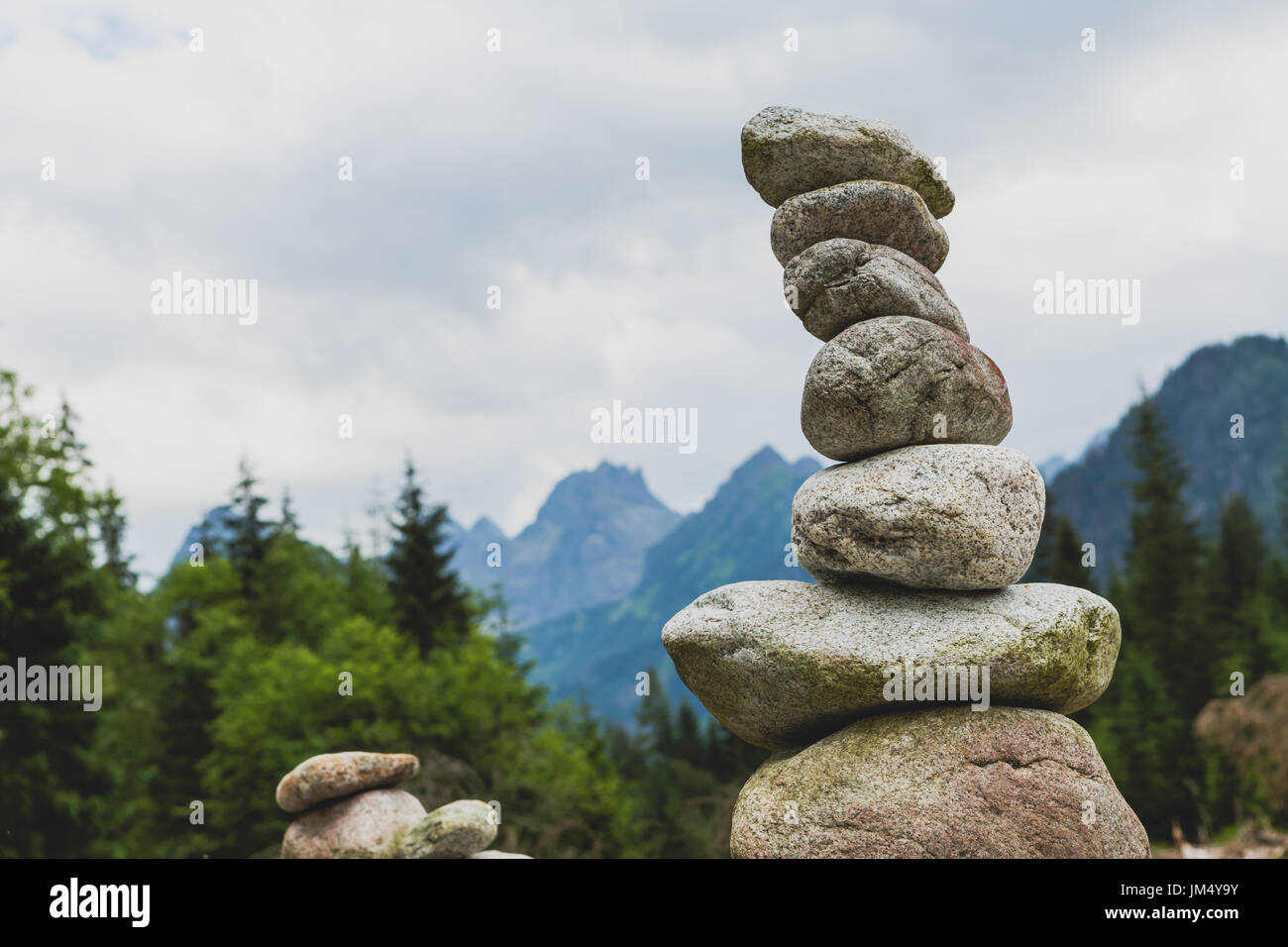 Stones balance, hierarchy stack over cloudy sky in mountains. Inspiring stability concept on rocks. Stock Photo