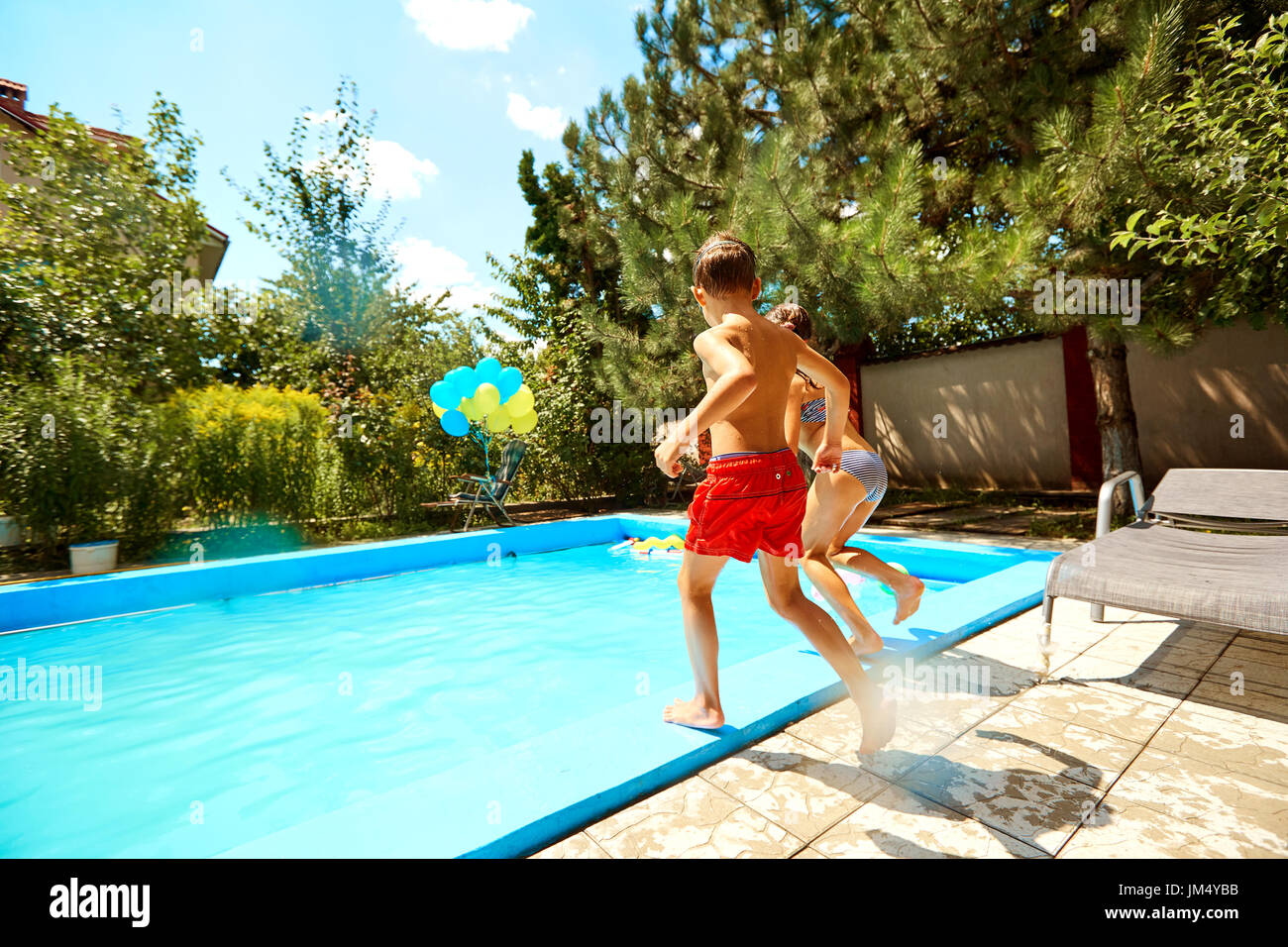 Children jump into the pool in the summer Stock Photo